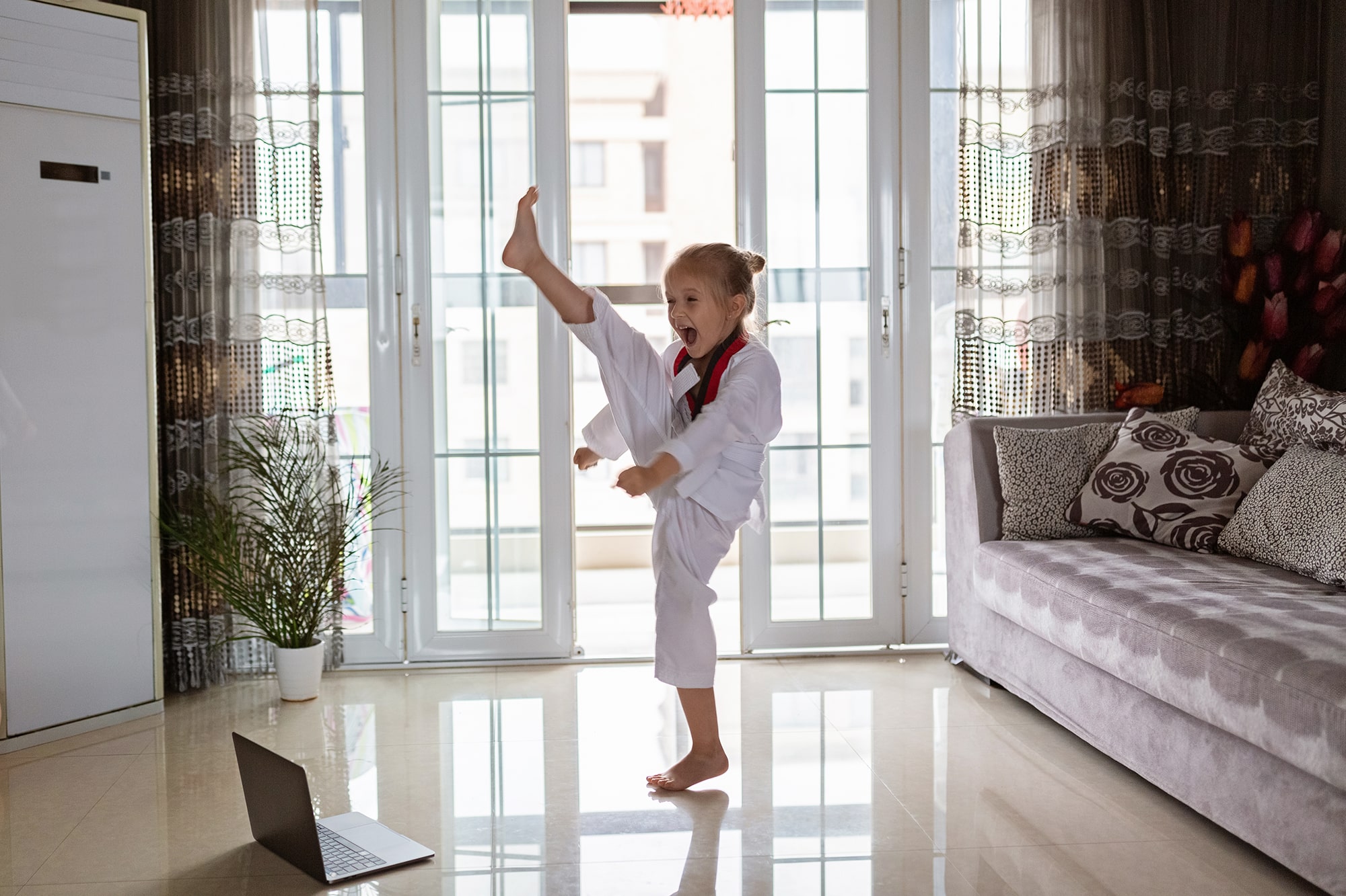 Student practicing martial arts at home while watching a video